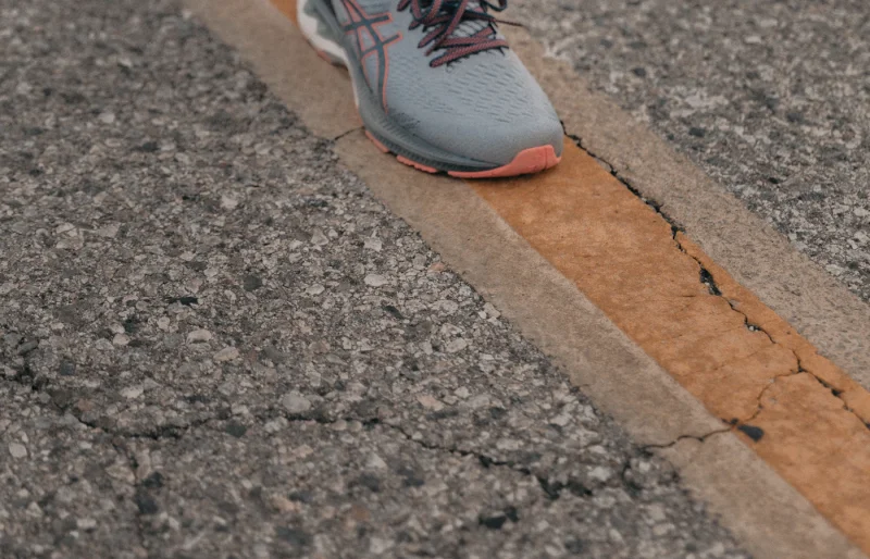 Close-up of a runner wearing gray running shoes on an asphalt road