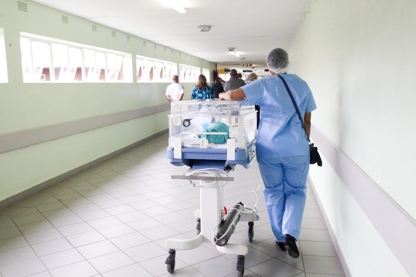 Nurse in blue scrubs walking down a hospital hallway during a long shift